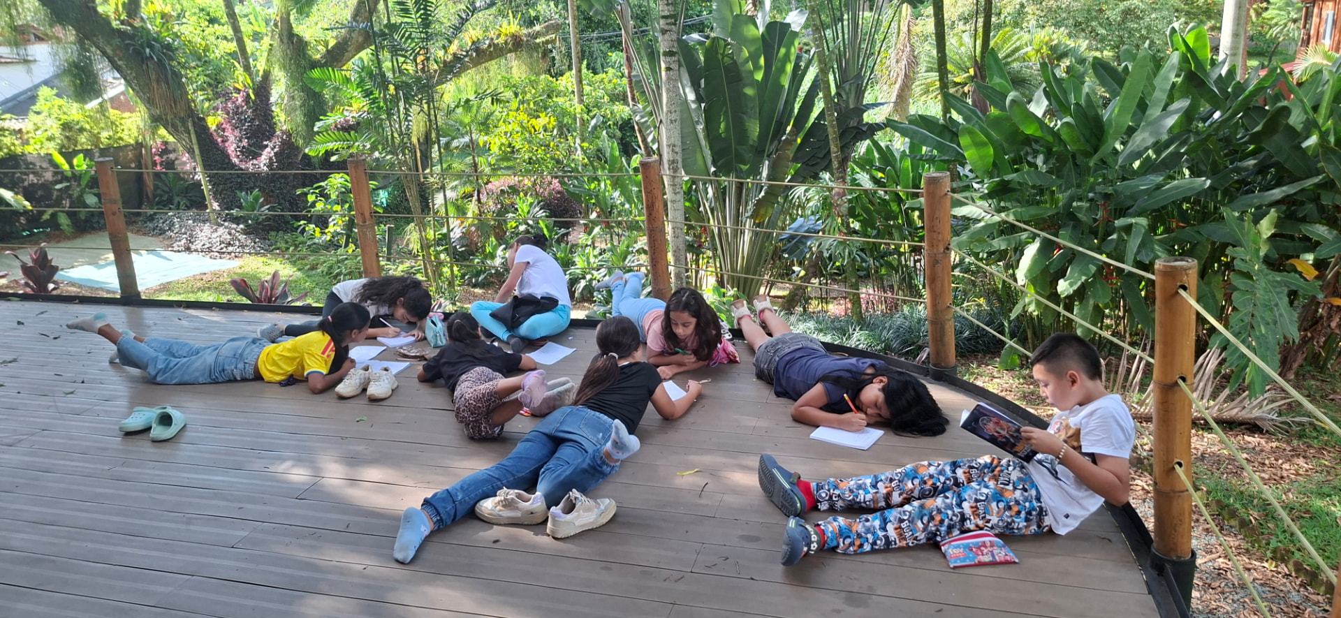 Niñas y niños haciendo la tarea al aire libre rodeados de naturaleza